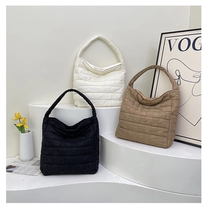 Three quilted tote bags in black, cream, and brown displayed in an elegant lifestyle scene