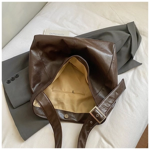 Detail view of large dark brown leather tote with magnetic closure and inner pocket