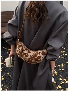 Fashionable cow print half-moon bag with gold chain strap shown from a back perspective