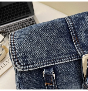 Gros plan sur le denim bleu délavé avec coutures orange et boucle en métal argenté