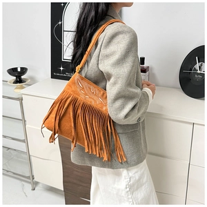 Detalle del bolso bandolera de ante naranja brillante con flecos largos y bordado blanco