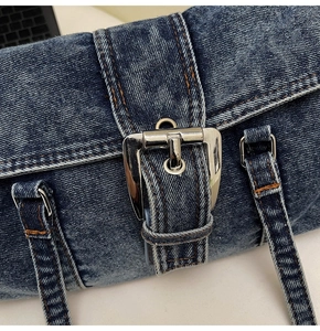 Détail d'un sac en denim bleu délavé avec coutures jaunes et boucle en métal argenté