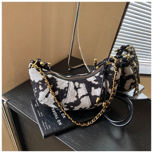 Detail of tweed half-moon bag with black and white patterns and gold chain strap