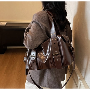 Vista posteriore di una borsa tote marrone scuro lucida con rivetti e fibbia in metallo