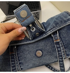 Détail du sac à bandoulière en denim lavé avec boucle métallique et coutures orange