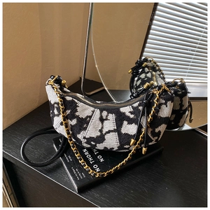 Detail of crescent shoulder bag with black and white tweed texture and gold chain strap