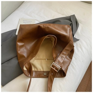 Detail view of large brown tote bag interior with zipper pocket and wide strap