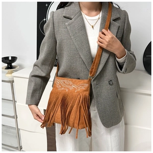 Détails des franges ethniques et de la broderie blanche sur un sac bandoulière en daim brun