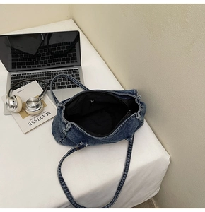 Intérieur du sac fourre-tout en jean bleu foncé avec poche zippée et détails argentés