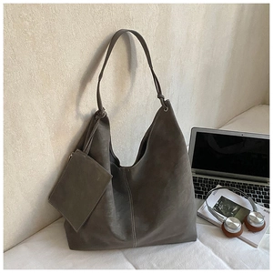 Detail shot of a dark grey matte leather hobo tote bag with matching small zipper pouch