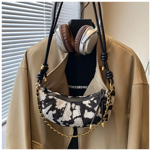 Detail of crescent crossbody bag with jacquard fabric, knot strap and gold chain accent