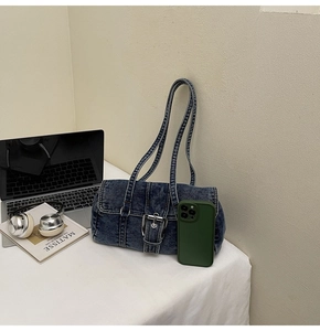 Détail du sac à épaule en jean délavé bleu avec boucle argentée sur bureau blanc