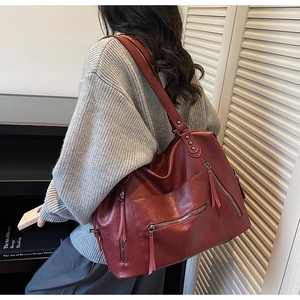 Detail of burgundy vintage tote bag showing glossy leather texture and fringe zipper charms