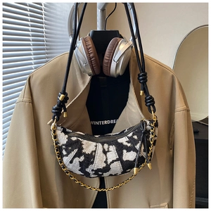 Detail of tweed crescent shoulder bag featuring black and white texture and chain strap