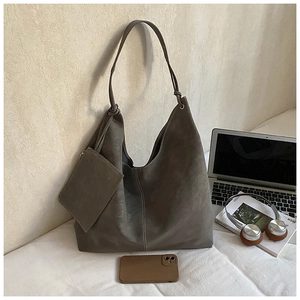 Detail of dark grey hobo tote bag with visible white stitching and matching pouch set