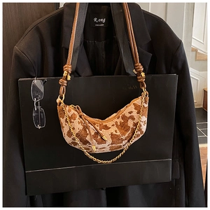 Detail of crescent shoulder bag with abstract texture and decorative gold metal chain