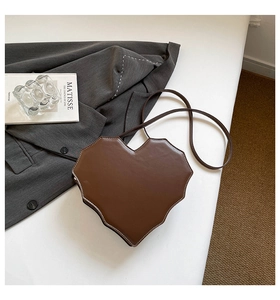 Detail einer braunen herzförmigen Tasche mit Zickzack-Kanten und weißen Ziernähten