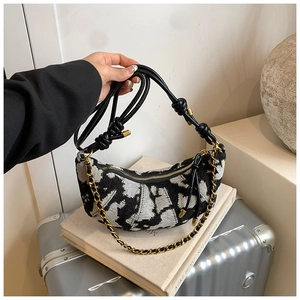 Close-up of black and white tweed crescent bag with knotted strap and gold chain detail