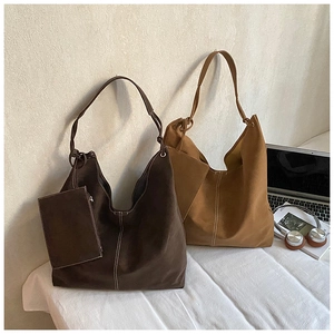 Detailed macro view of large suede tote bags in dark coffee and caramel with contrast stitching