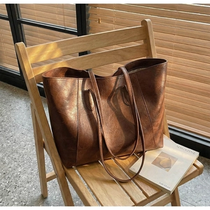 Detailed texture of brown vintage faux leather tote bag on a wooden chair