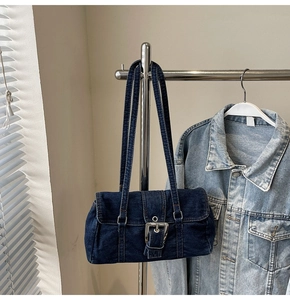 Détail de la texture denim délavé et boucle argentée sur le sac à bandoulière bleu