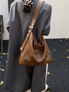 Brown leather tote bag with silver buckle strap shown in an autumn street style view