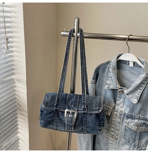 Détail du sac à épaule en denim bleu délavé avec une grande boucle en métal argenté