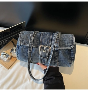 Détail d'un sac bandoulière en jean délavé vintage avec boucle argentée et fines brides