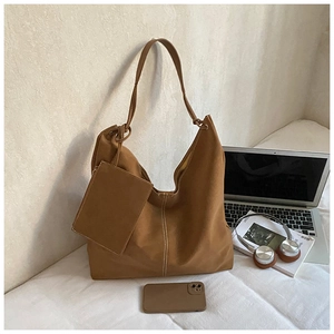 Brown large tote bag with matching pouch and white stitching detail on white bedding