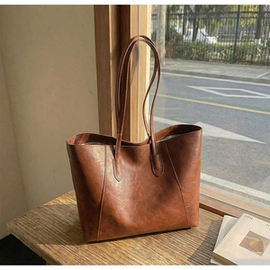 Close-up of vintage brown tote bag with pleated leather texture on wooden table