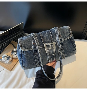 Détail de sac bandoulière en denim lavé avec boucle en métal argenté et texture vintage