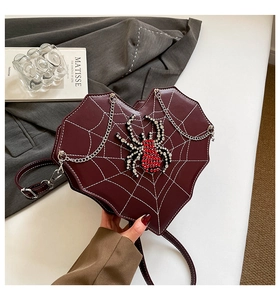 Detail der burgunderroten herzförmigen Tasche mit Spinnennetznaht und Strassspinne Anhänger