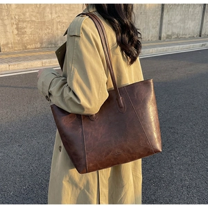 Detailed view of large dark brown tote bag with vintage texture worn on shoulder