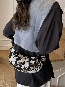 Fashionable black and white tweed hobo shoulder bag with golden chain strap on model