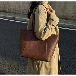 Detail of the vintage dark brown leather tote bag showing fine texture and logo