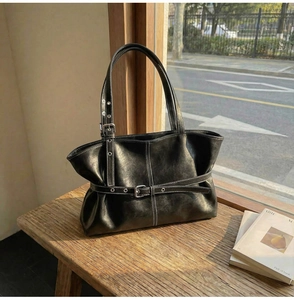 Détail du cabas vintage en cuir noir avec boucle argentée et surpiqûres blanches contrastées