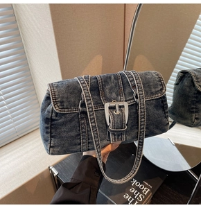 Détail de la texture du denim délavé et de la boucle métallique sur le sac à bandoulière