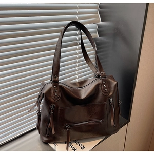 Detailed view of dark brown vintage leather tote bag with multiple zippers and studs