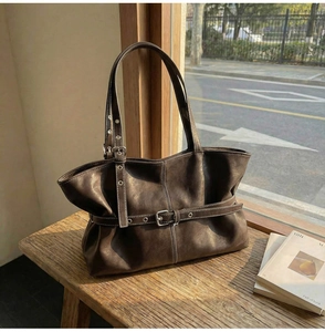 Détail du sac cabas en cuir marron vintage avec boucle argentée réglable sur banc en bois