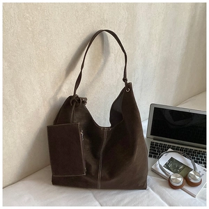 Detail of dark chocolate suede tote bag with contrast stitching and small charm pouch