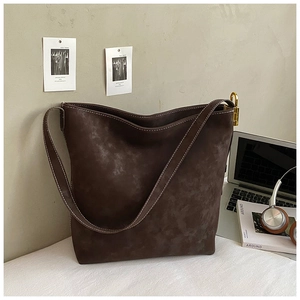 Detailaufnahme der braunen Wildledertasche mit Kontrastnähten und goldenen Metallteilen