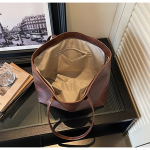 Detailed interior of a vintage brown tote bag showing light grey lining and zipper pocket