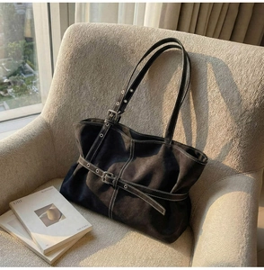 Détail du sac cabas noir avec coutures contrastées blanches et une sangle à boucle métal