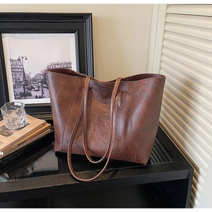 Detailed close-up of brown faux leather tote bag texture and long shoulder straps