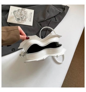 Detailansicht der weißen herzförmigen Tasche mit silbernen Reißverschlüssen und Innenfutter