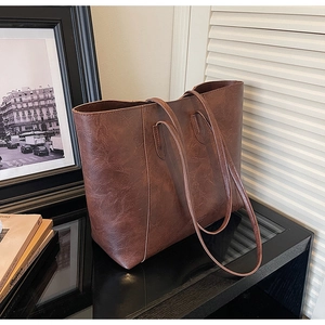 Detail of dark brown leather tote bag with vintage texture and minimalist slim shoulder straps