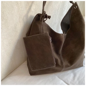 Detail of dark brown suede tote bag featuring white contrast stitching and knotted strap