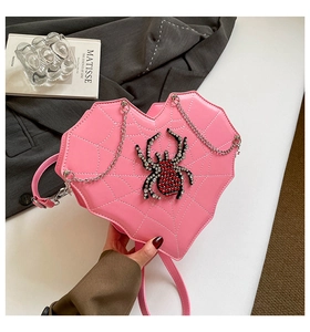 Detail der rosa herzförmigen Tasche mit weißem Spinnennetzmuster und Spinnen-Schmuckstein