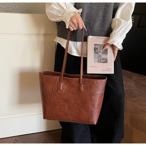 Close-up of a large brown vintage tote bag with fine stitching and slim shoulder straps