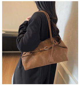 Detalle de bolso hobo de ante marrón con pliegues naturales y correas de hombro